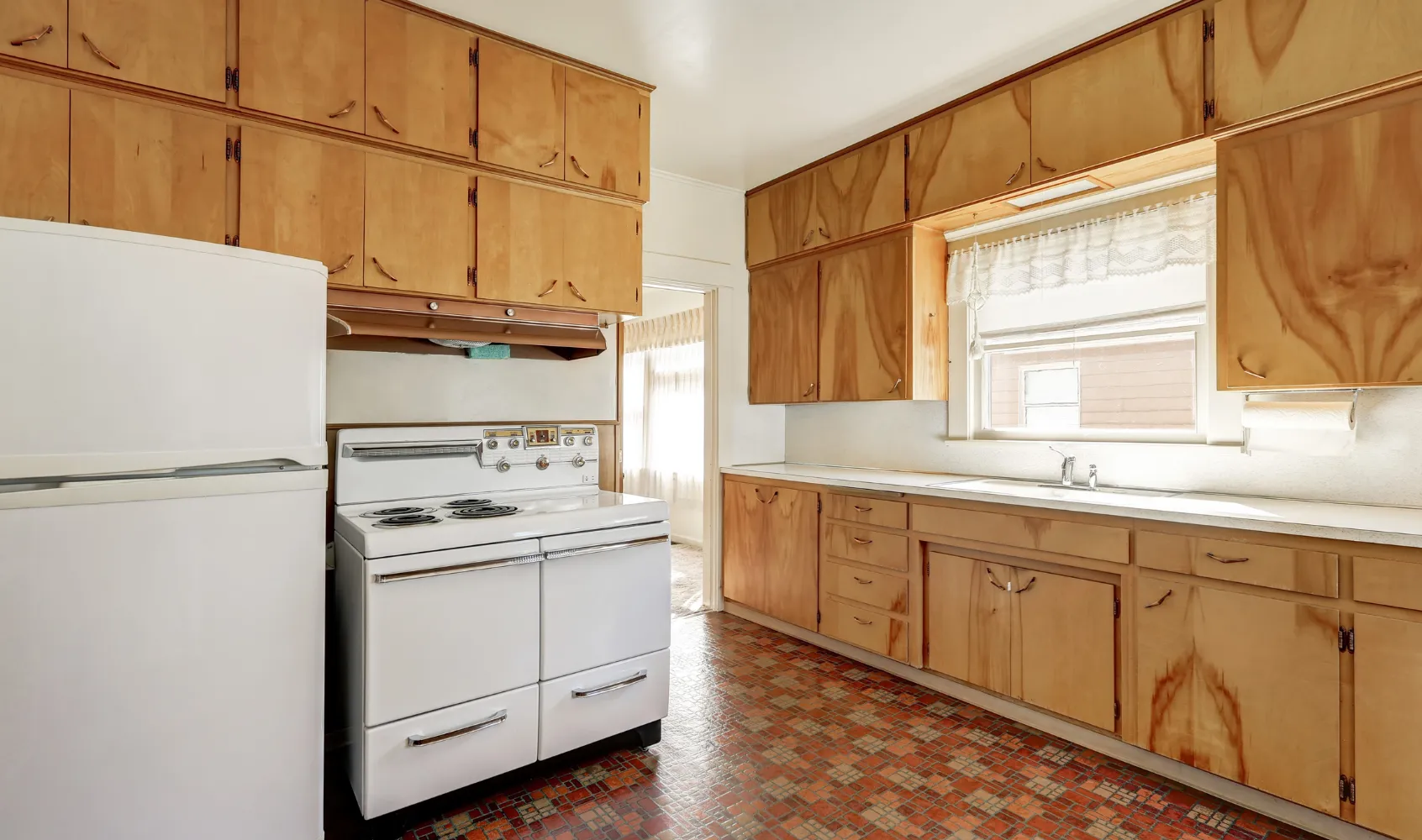 Outdated kitchen in Los Angeles with old wood cabinets, vintage stove, limited storage, and worn flooring before renovation