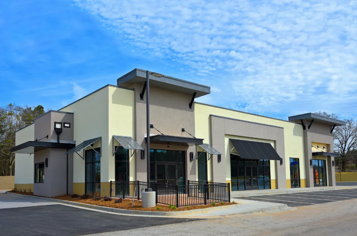 Modern commercial construction project in Los Angeles featuring newly built retail building exterior with storefront glass and parking area