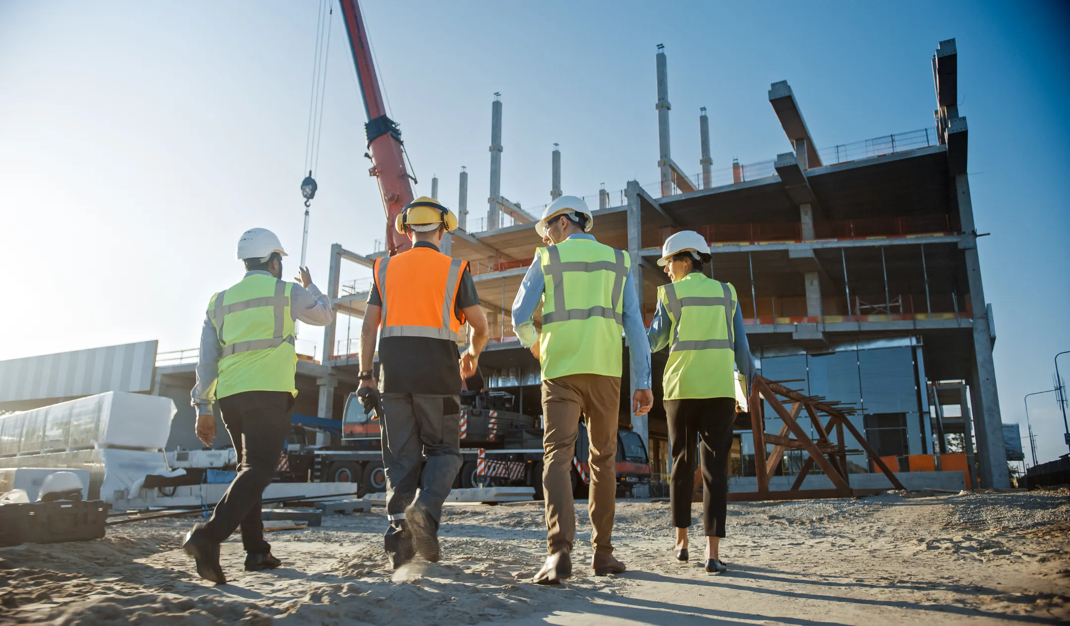 Commercial construction project in Los Angeles with contractors and engineers inspecting large building structure and crane operations on site