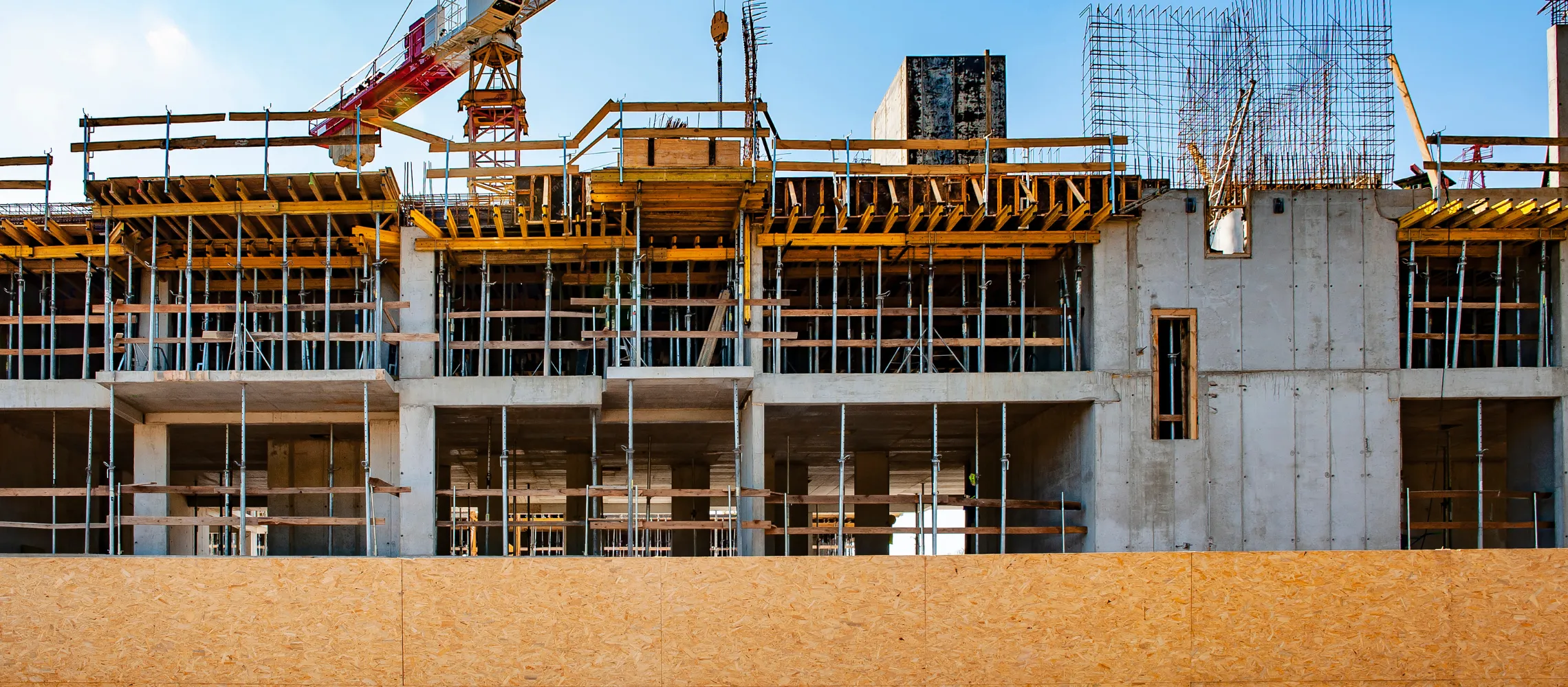 Commercial construction site in Los Angeles with concrete building structure, crane, and development crew working on project