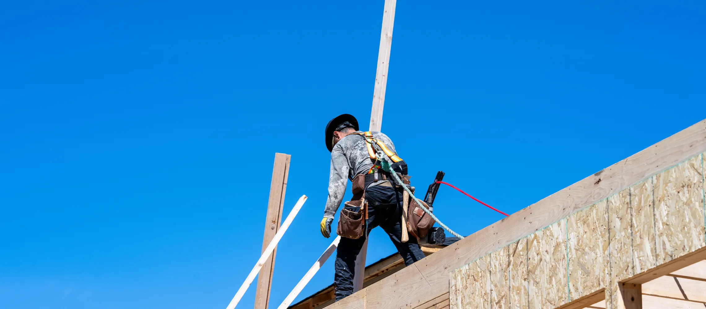 General contractor in Los Angeles working on wood framing structure at residential construction site with safety gear and tools