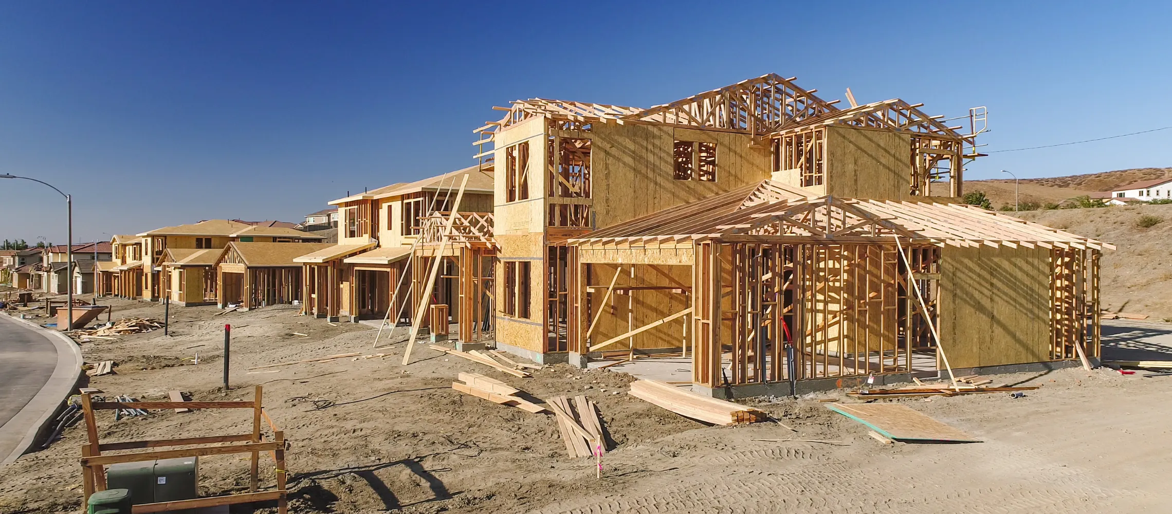 New home construction site in Los Angeles with residential framing and multiple houses under development during sunset with crane and construction crew working on project